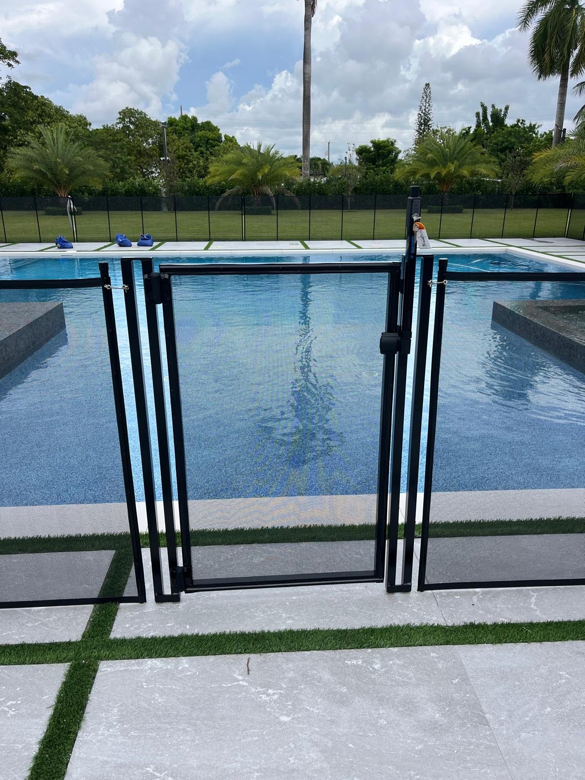 Black removable mesh pool safety fence with self-locking gate.