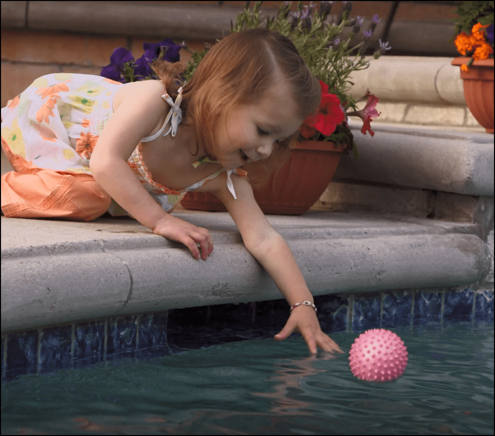 Little girl leaning over pool edge