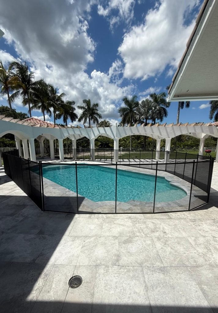Luxury Pool Safety Fence Installation in Boca Raton, FL Black removable mesh pool safety fence installed around a luxury residential pool in Boca Raton, Florida