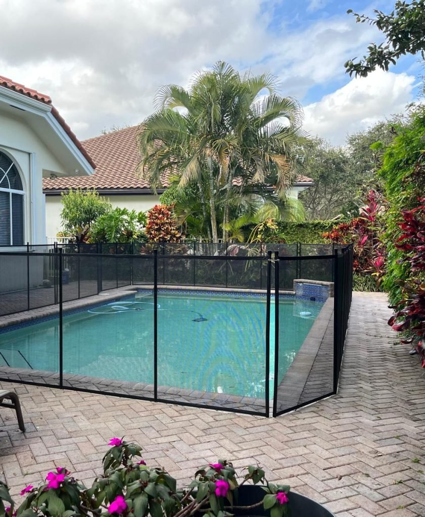Black Mesh Pool Safety Fence Installation in West Palm Beach Black removable mesh pool safety fence installed around a backyard swimming pool in West Palm Beach, FL.